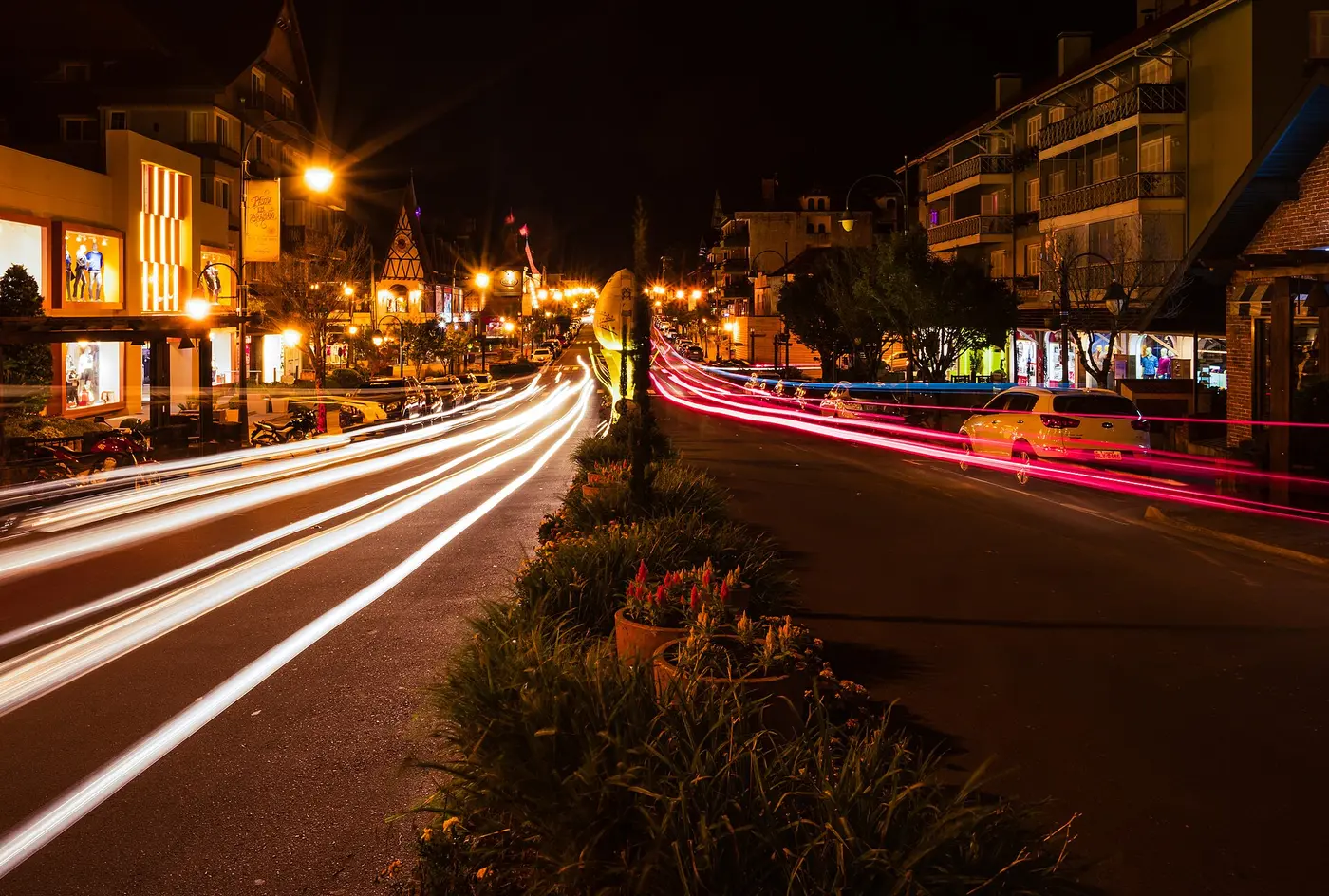 Avenida arborizada no centro de Gramado à noite com luzes